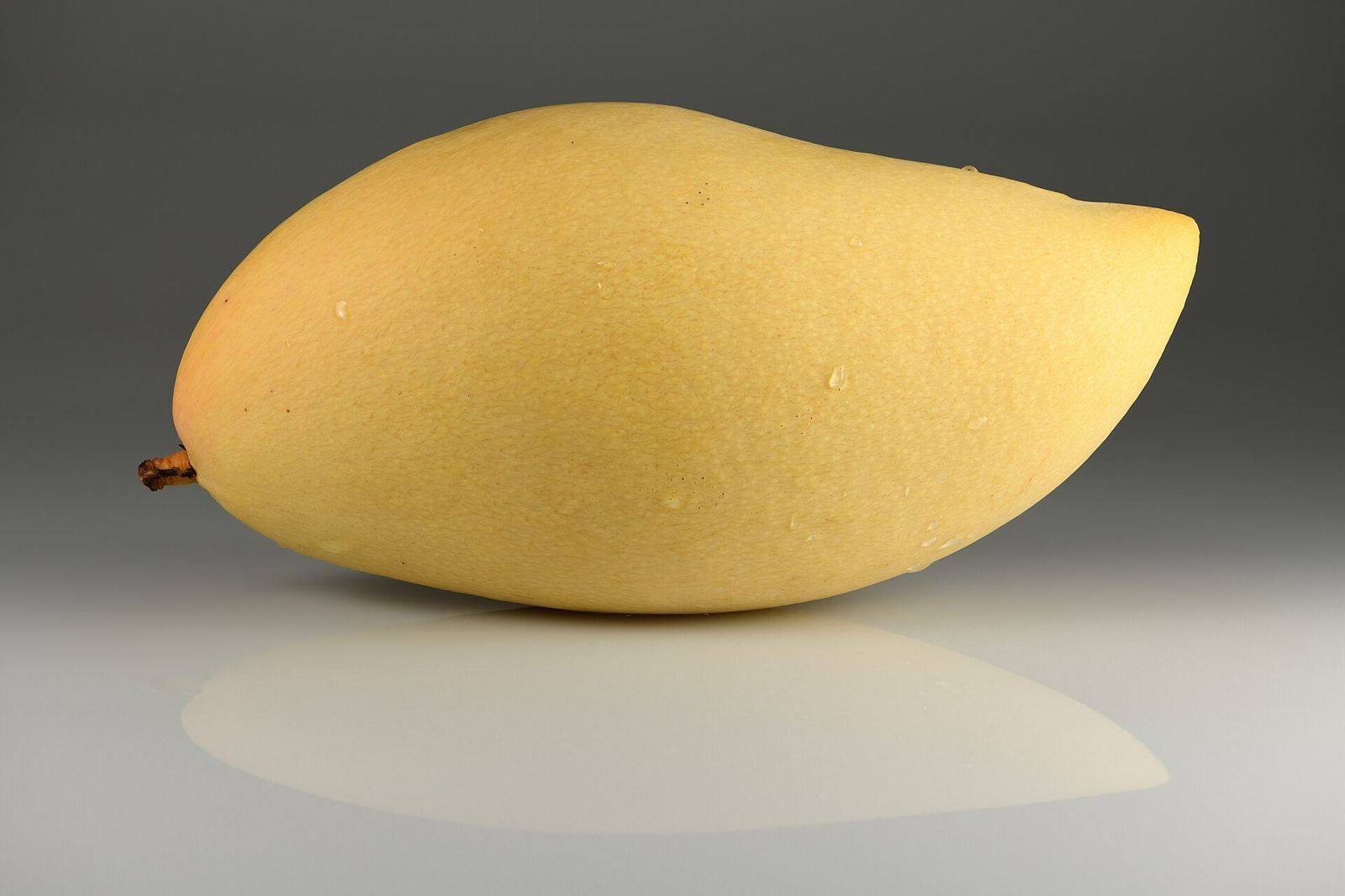 A ripe Nam Doc Mai mango: long, slender, curved fruit with smooth yellow skin
